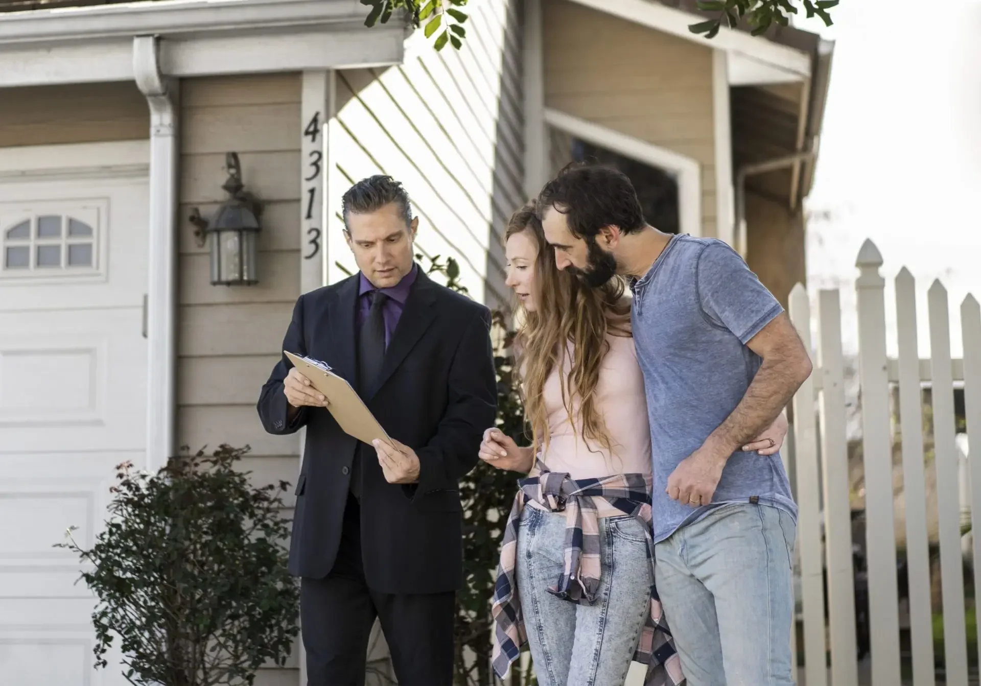 Real estate agent with couple outside house.